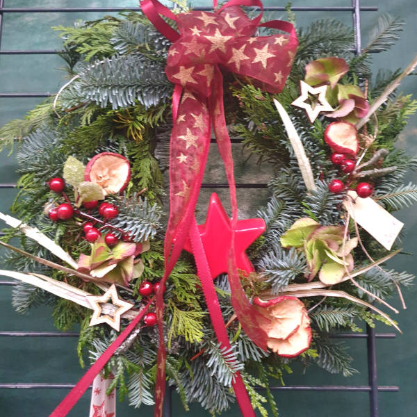 Ein klassischer Adventskranz zum Anängen an die Tür in den Farben rot und gold.
