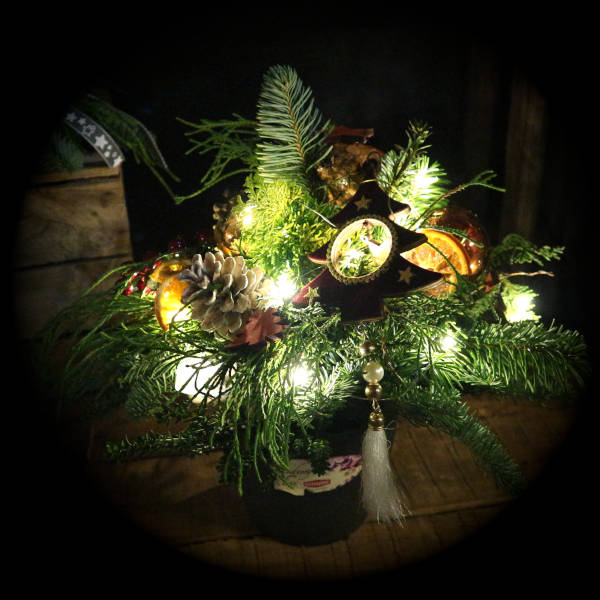 Naturnah dekoriertes Adventsgesteck mit Lichterkette.