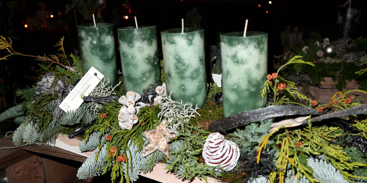 Adventsgesteck mit grünen Kerzen.