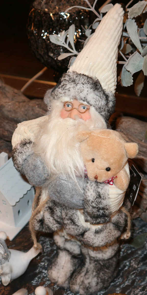 Dekorationsfigur: Weihnachtsmann im verschneiten, hellen Anzug.