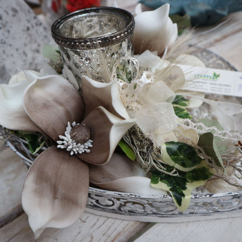 Ein weißes Tablett, welches mit an Magnolienblüten erinnernden Kunstblumen dekoriert wurde.