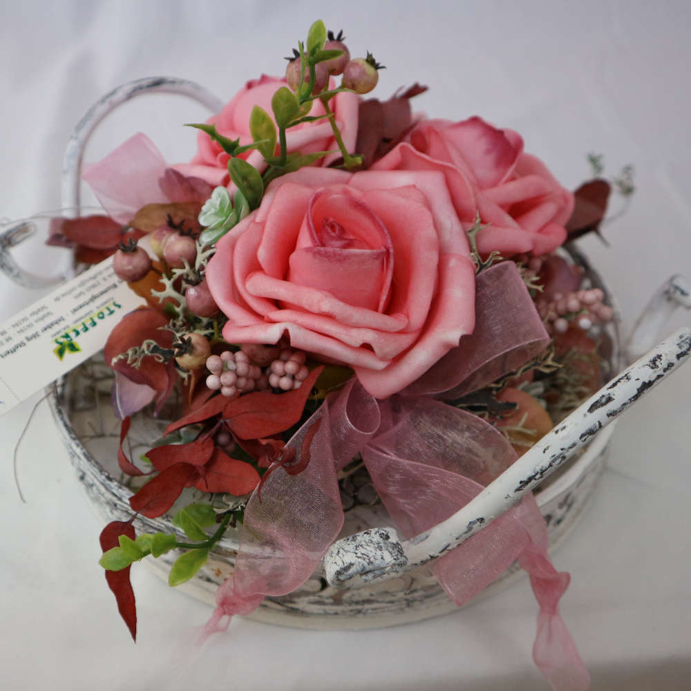  Ein Dekotablett im Vintage-Stil, welches mit Kunstblumen und Kunstbeeren in rosa dekoriert wurde. 
