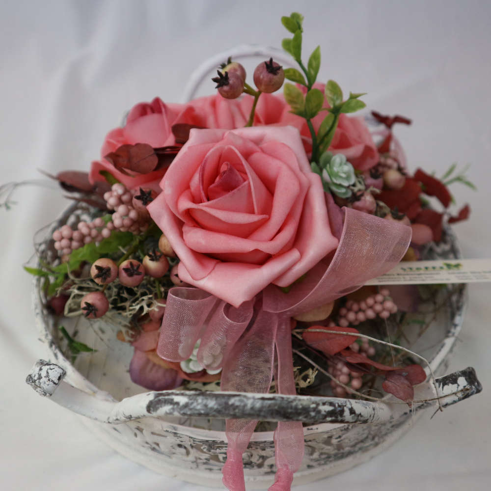 Ein Dekotablett im Vintage-Stil, welches mit Kunstblumen und Kunstbeeren in rosa dekoriert wurde.