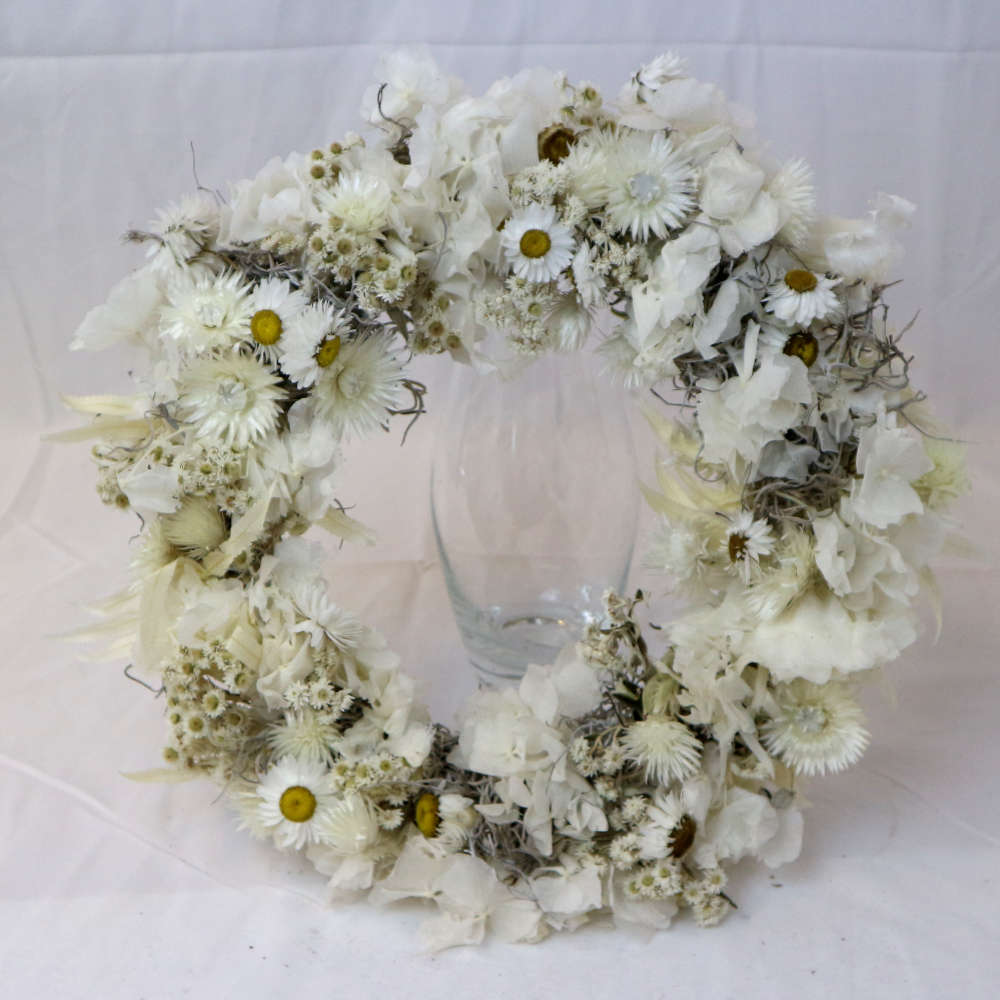  Ein weißer Kranz aus getrockneten Blumen. Unter anderem wurden Strohblumen und Hortensieblüten verwendet. Streng gewickelte Variante. 