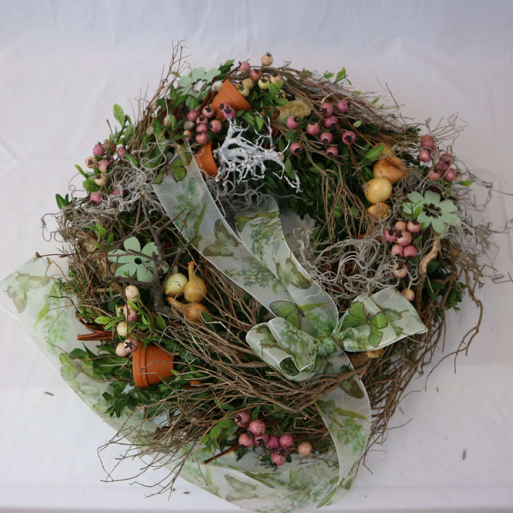  Ein rustikaler Kranz zum Hinlegen oder Anhängen. Bestehend aus Moos, Frühlingszweigen, rosa Kunstbeeren und Minitöpfchen. 