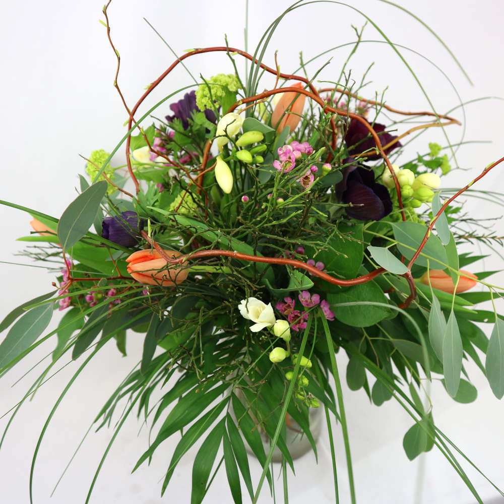  Ein locker gebundener, bunter Blumenstrauß mit Tulpen, Mohn, Fresien und Schneeballblüten. 