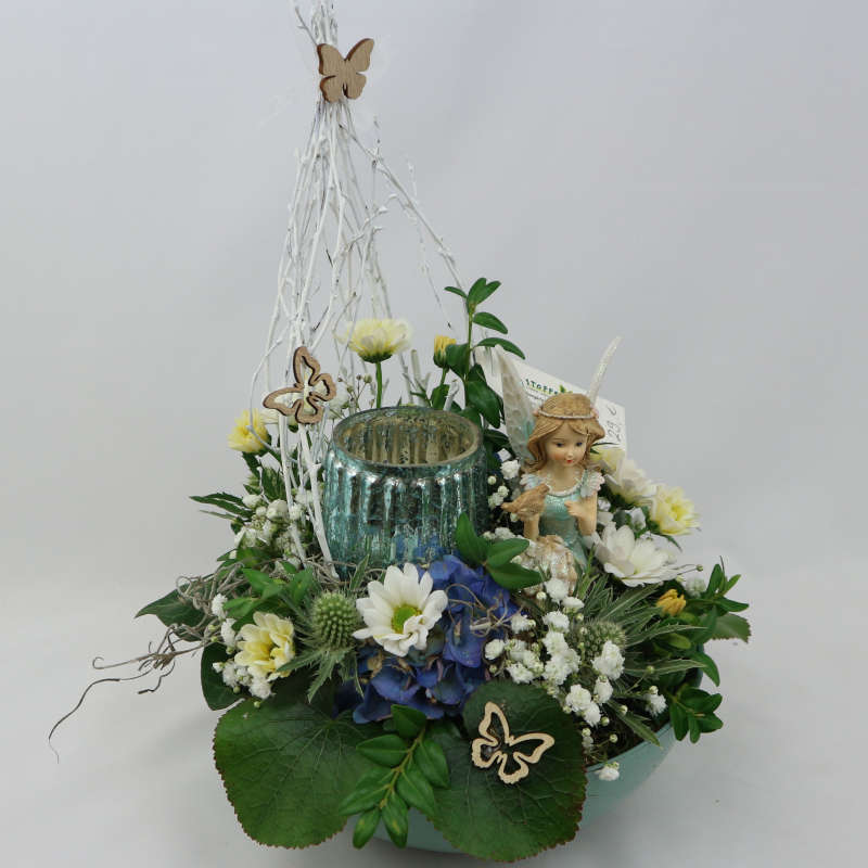 Ein sattgrünes Gesteck aus Frischblumen mit einer mintgrünen Elfe und einem Kerzenglas.