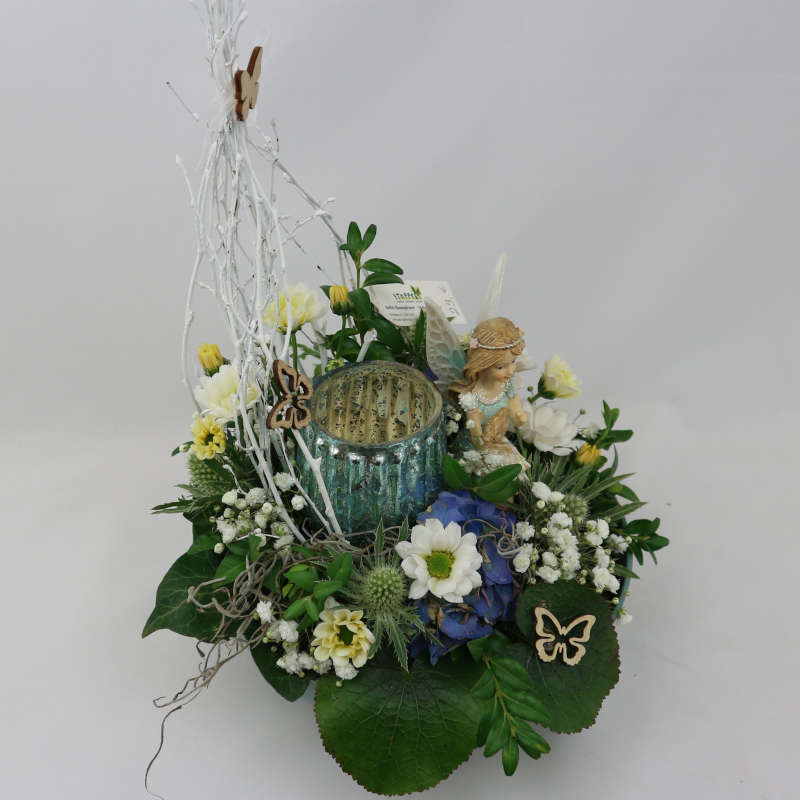 Ein sattgrünes Gesteck aus Frischblumen mit einer mintgrünen Elfe und einem Kerzenglas.