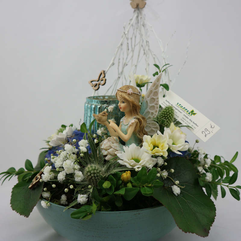 Ein sattgrünes Gesteck aus Frischblumen mit einer mintgrünen Elfe und einem Kerzenglas.