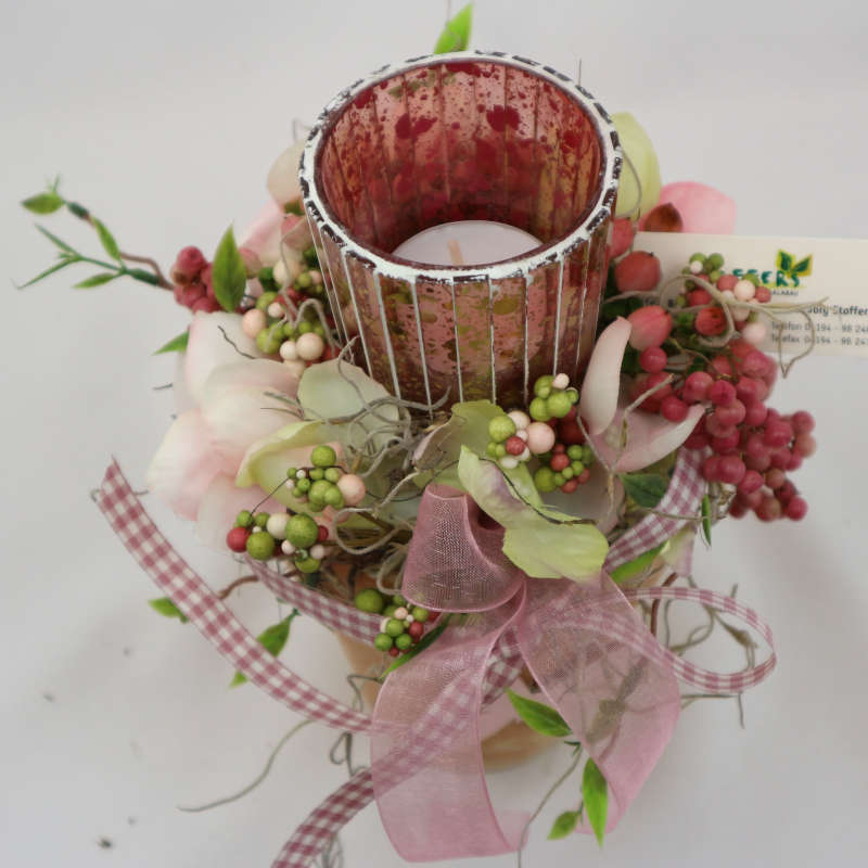 Kerzenglas im kleinen Tontopf, umgeben von Kunsthortensienblüten, Kunstbeeren und getrockneten Pfefferzweigen. 