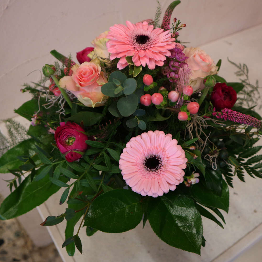 Ein großer, kompakt gebundener Blumenstrauß, bestehend aus rosa Gerbera, aufstrebenden Veroknika und rosa Rosenblüten.