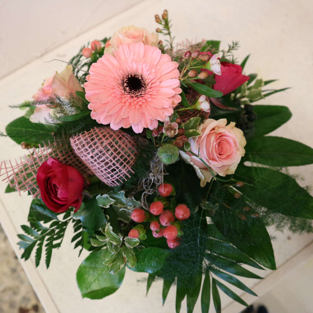 Ein kleiner, kompakt gebundener Blumenstrauß, bestehend aus rosa Gerbera, aufstrebenden Veroknika und rosa Rosenblüten.