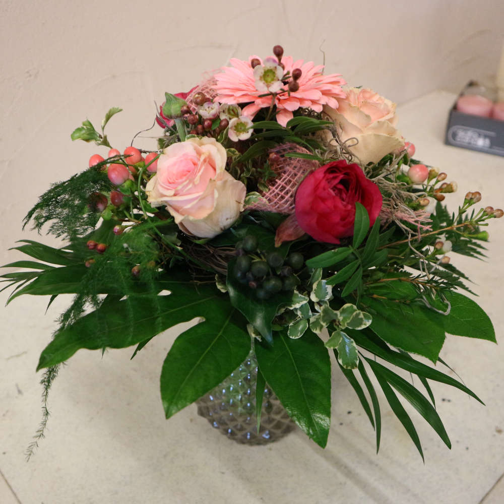 Ein kleiner, kompakt gebundener Blumenstrauß, bestehend aus rosa Gerbera, aufstrebenden Veroknika und rosa Rosenblüten.