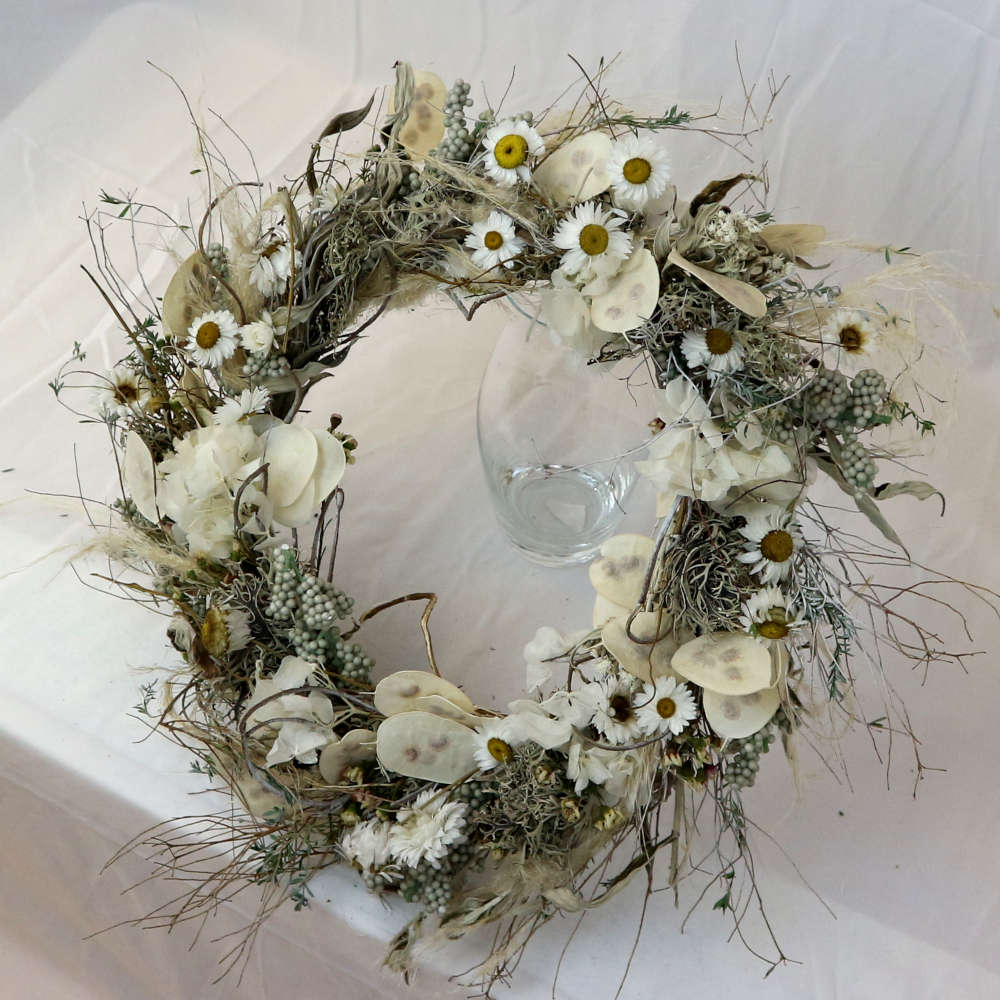 Ein weißer Kranz aus getrockneten Blumen. Unter anderem wurden Strohblumen und Hortensieblüten verwendet. Locker gewickelte Variante.